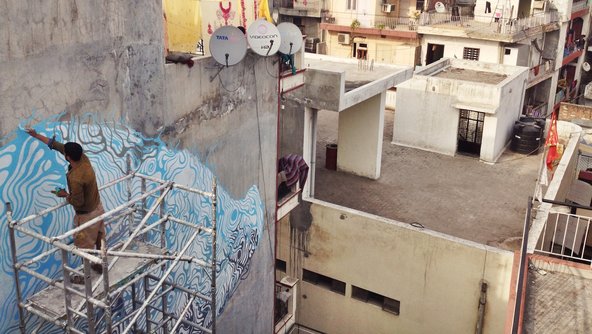 Max Bearak. Amitabh Kumar painting a wall in Shahpur Jat, one of South Delhi’s urban villages